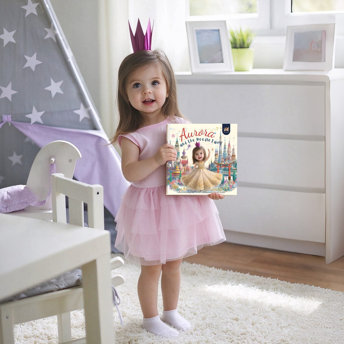 Little girl in a paper crown and pink tutu holding her personalized Elfink storybook Aurora and the Needle Fairy with her own photo on the cover